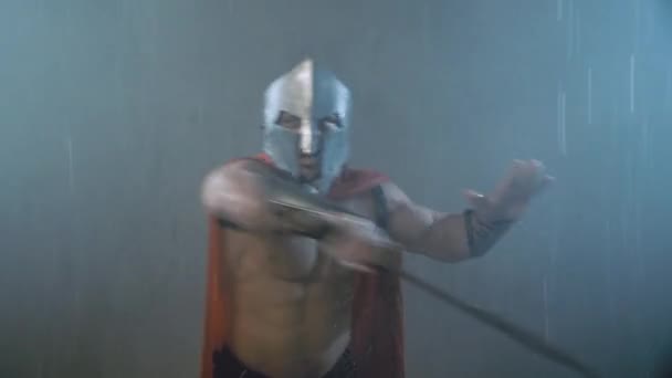Espartano mostrando ataque usando lâmina sob chuva. — Vídeo de Stock