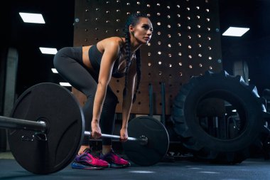 Beden eğitiminde halter kullanarak ağırlık kaldıran bir kadın..