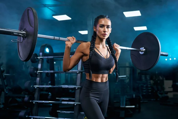 Vrouw met lange halter op de schouders in de sportschool. — Stockfoto