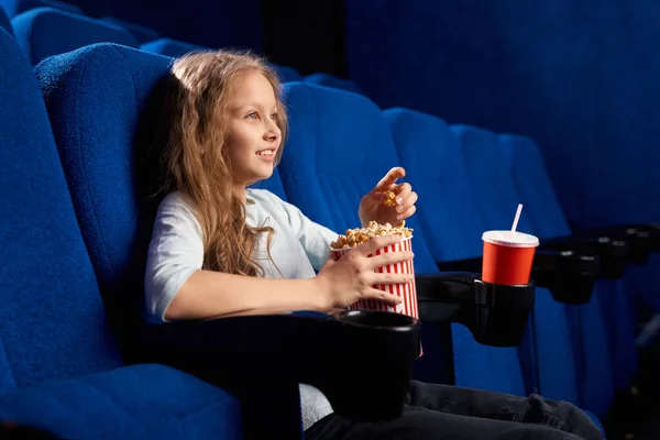 Piccola ragazza caucasica guardando film nel cinema. — Foto Stock