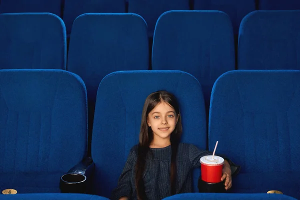 Μικρό χαμογελαστό κορίτσι που κάθεται σε άδειο σινεμά. — Φωτογραφία Αρχείου