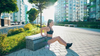 Genç sporcu yedek kulübesinde trisepsle dalma alıştırması yapıyor..