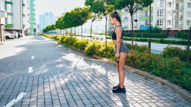 Kız dışarıda direniş bandı kullanarak bacak çalıştırıyor..