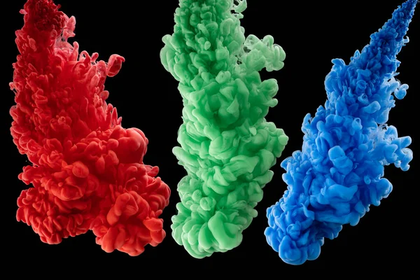 Suda kırmızı, yeşil ve mavi mürekkep. Mürekkep suda tepki veriyor. Yaratıcı. Siyah arka plan. RGB rengi