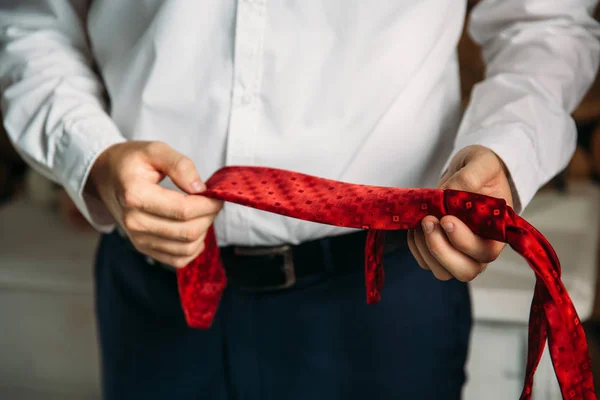 Empresário de close-up em camisa branca, noivo segurando gravata vermelha em suas mãos. Conceito de homens elegância elegante roupas . — Fotografia de Stock