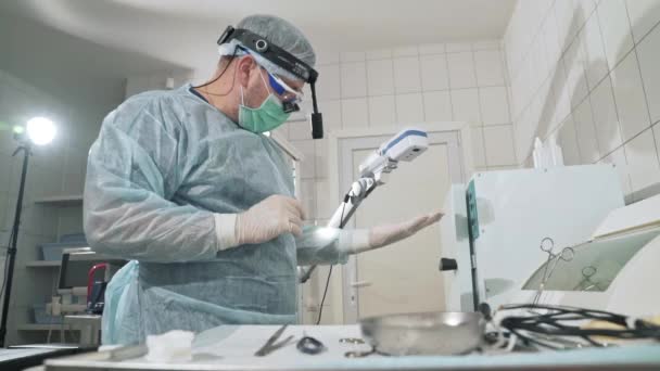 在医院工作的外科医生在手术前消毒医疗器械。戴眼镜的医生, 专业的衣服, 不育的面具和睡衣。健康的概念, 工作在 — 图库视频影像
