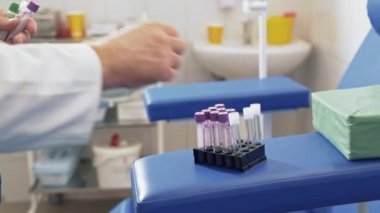 Yakın çekim bir doktor bir klinik laboratuvar kan testi yürüten ve test tüpleri bir konteyner içine koyar. Tıbbi ekipman ile bir hastanede cerrah bir beyaz steril sabahlık içinde çalışır.