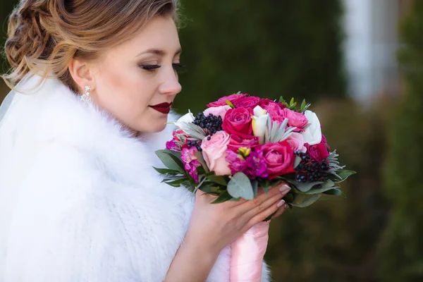 Perfil close-up tiro noiva admira um buquê de flores e respira o aroma de rosas. Uma menina com uma maquiagem delicada e lábios escarlate brilhante . — Fotografia de Stock