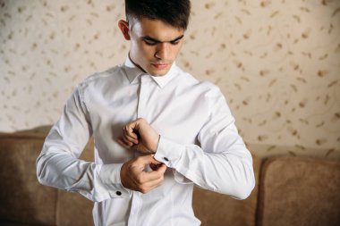 Bir iş adamı için iş elbiseleri. Yoğun bir adam kol düğmesi onun beyaz gömlek elbiseler. Esmer modeli şık bir gömlek.