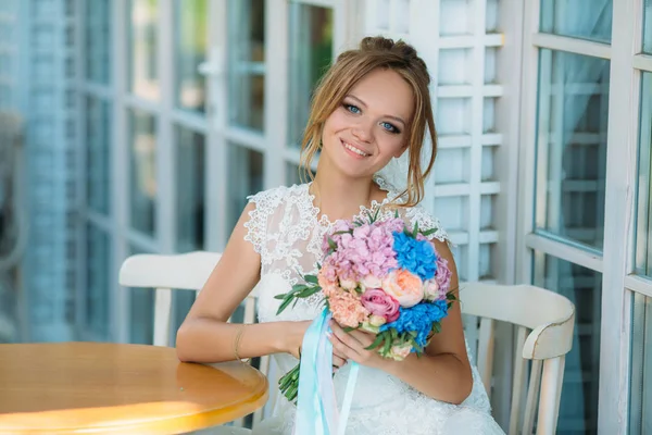 Die blonde Braut mit den strahlend blauen Augen lächelt breit. ein Mädchen mit einem Blumenstrauß ist glücklich, einen geliebten Menschen zu heiraten. — Stockfoto