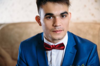 Kahverengi gözlü adam biraz utandı ve kameraya doğru görünüyor. Çiller ve siyah saçlı Genç bir adamla yakın bir portresi. Kırmızı Kelebek çok bir adam mavi takımı için uygundur.