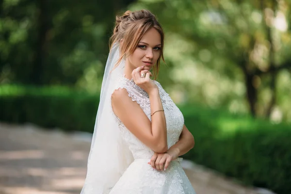 Portréja egy furfangos menyasszony, aki fogantatott valamit. Egy lány pózol egy csipke esküvői ruha. A szőke férjhez ma. — Stock Fotó