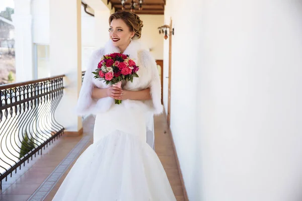 Jovem segurando um buquê de rosas rosa e vermelha e olhando para a distância, sorrindo amplamente. Uma menina com batom brilhante ri e se alegra no casamento . — Fotografia de Stock