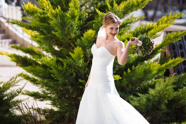 Ein glückliches Mädchen läuft herum und spielt im Garten inmitten des Grüns, lächelt und genießt die Schönheit der Natur und ihre Hochzeit. — Stockfoto