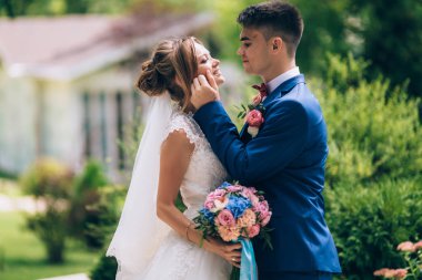 Adam dikkatle için gelin saçı ayarlar ve ona sevgiyle bakar. Gülümsüyor ve eşi bir gelinlik kız görünüyor.