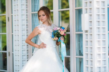 Bir kız elini onun kemer üzerinde tutarak ve bir buket çiçek ile poz. Güzel bir sarışın mavi gözlü evleniyor.