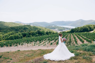 Kız beyaz bir gelinlikle doğada, üzüm bağları, dağlar, ovalar ve göller bakarak yürüyor. Nişanlısı hakkında düşünüyor.