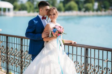 Bir nehir arka planı poz mutlu yeni evliler. Adam gelinler saç kokusu tadını çıkarıyor. Sevgili biri evlenmek mutlu bir kızdır. Bir kız bir dantel gelinlik bir buket ile