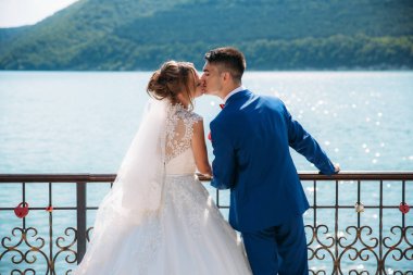 Yeni evliler arka planı yeşil dağ ve nehir iskele şefkatle öptü. Onlar bugün evlendi ve bir aile oldu mutlu olduklarını