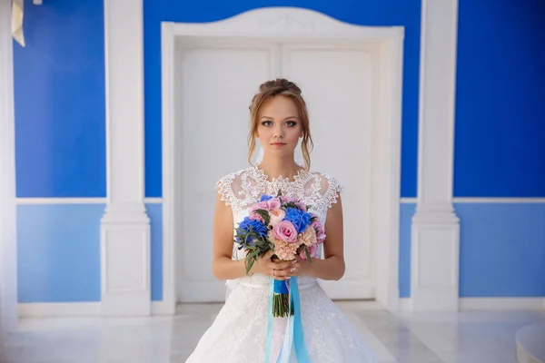 Atirar o rosto cheio da noiva com um buquê exuberante de flores está olhando abertamente para a câmera. A menina no vestido de noiva se preocupa antes da cerimônia de casamento . — Fotografia de Stock
