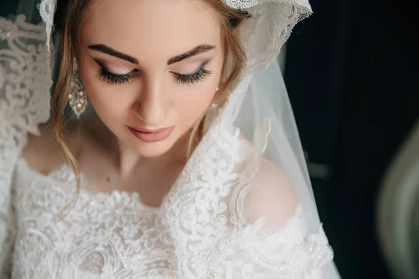 Close-up of a girl face that looks down. Beautiful natural make-up of eyes, long thick eyelashes, white large earrings with stones. — Stock Photo, Image