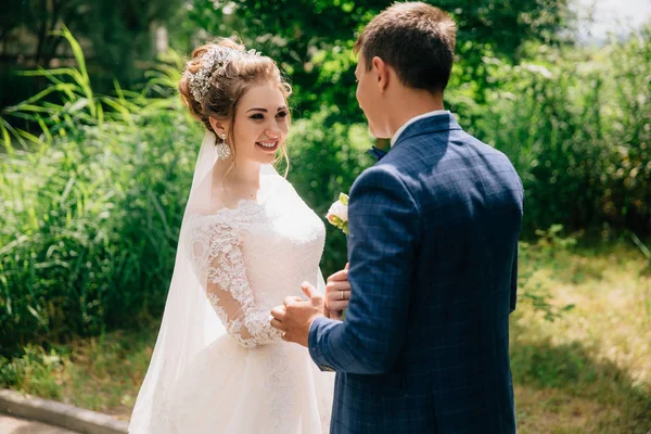 La novia ajusta su chaqueta a su prometido y le sonríe. Los amantes pasan tiempo fuera de la ciudad . —  Fotos de Stock