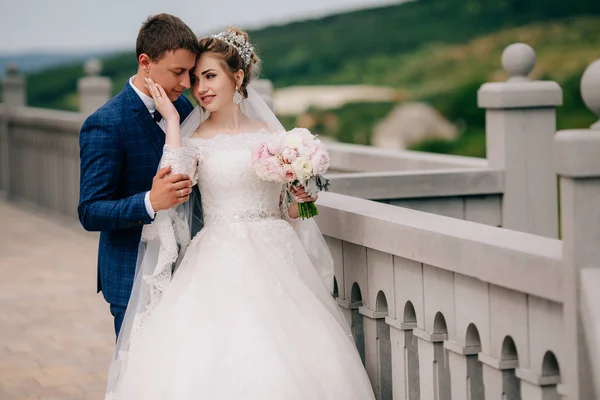 La esposa roza suavemente a su marido en la mejilla. Una mujer le da a un hombre apoyo y cuidado, ternura y calidez. Los recién casados abrazan y admiran la naturaleza . —  Fotos de Stock