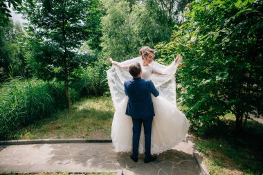 Damat gelini kollarını kaldırdı ve çember ve kız zevk ve işlemeli onu peçe yayılıyor.