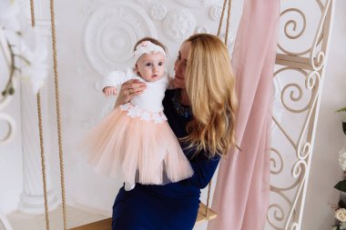 Uzun saçlı bir ince sarışın bir salıncağa oturur ve küçük kızı, kim onun kollarında olduğunu inceliyor. Küçük bir ilgi ile etrafına bakıyor ve oda çalışmaları.