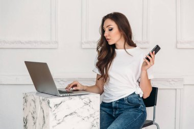 Güzel bir çevirmen bir tablo bir kafede çalışıyor. Kız telefonla onun cevap bekliyorum müvekkili için bilgi arayan üzerinde konsantre. Meslekler, insanlar, modern teknoloji