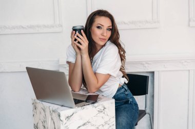 Şık genç kız serbest meslek çalışma bilgisayar, cevap telefon görüşmeleri ve sms her gün ışık elbise giymiş, kahve içer ve neşeli geliyor.