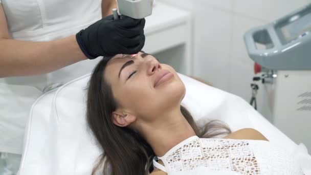 Close-up voert de arts schoonheidsspecialist in een badjas en handschoenen laser procedures op het gezicht van een vrouwelijke patiënt. Plastic en ectatic chirurgie, skin resurfacing in de kliniek. Medische — Stockvideo