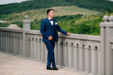 Şık elbiseli bir adam görüntüleme platformu elini kolunu sallaya dönüyor ve iyi hava düğün gününde sahiptir.