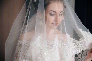 Bir close-up gelin duvak koymak. Beyaz dantel kumaş ile güzel bir kızın yüzü.