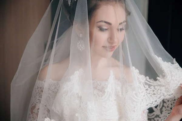 Un gros plan de la mariée portant un voile. Le visage d'une belle fille à travers un tissu de dentelle blanche . — Photo