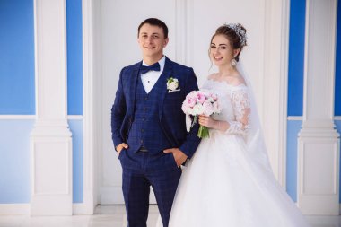 Yeni evliler gülümseyen, sıkı şık elbiseli adam ve bir buket ile kabarık beyaz elbiseli kız tören salonu, girmek için gidiyoruz.