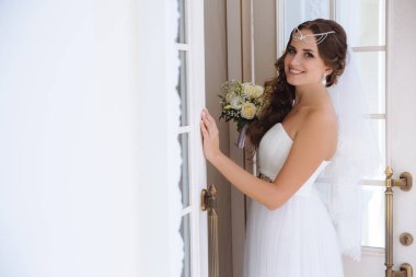 Mutlu gelin tören salonu, gülümsüyor girmek hazırlar ve onu düğün uket tutar, saçlarını lalatic ile süslüdür.