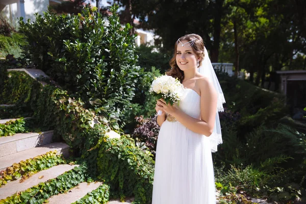 Uma noiva grávida do tipo europeu posa com um buquê de rosas brancas, organizou um casamento no estilo grego . — Fotografia de Stock