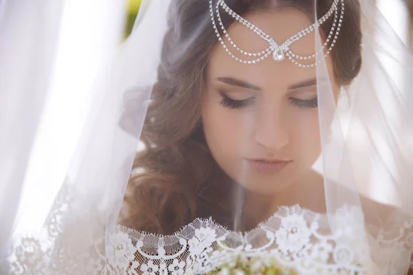 Eine Nahaufnahme der griechischen Braut bedeckte ihr Gesicht mit einem weißen Schleier und senkte ihre großen Augen nach unten. — Stockfoto