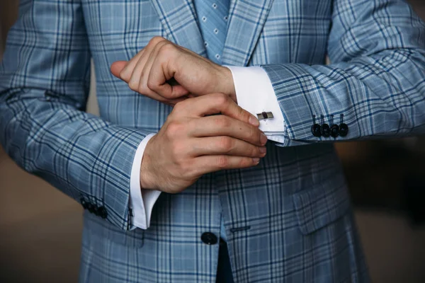 Mãos de noivo fechadas seguram abotoaduras. Roupa de cavalheiro elegante, camisa branca e cinto preto. conceito de roupa de trabalho clássico no escritório, jóias . — Fotografia de Stock