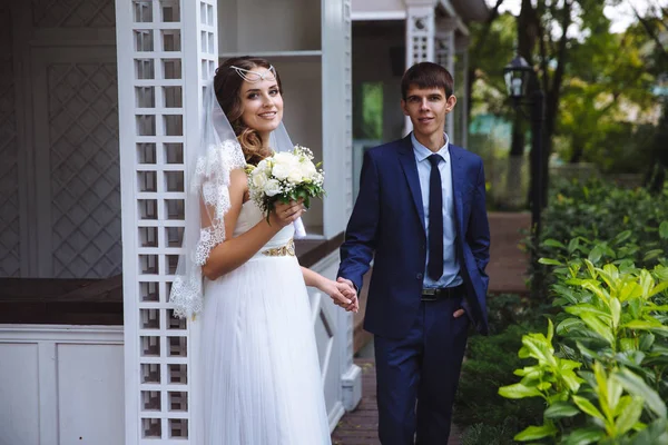 Die Frischvermählten kamen in ihr Landhaus, um dort das Wochenende zu verbringen. der Ehemann hält seine Frau an der Hand, beide sind in Hochzeitskleidung gekleidet. — Stockfoto