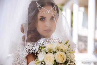 Bir close-up yüzü örtülü bir peçe yeşil gözlü bir gelinin, saçlarını lalatic, makiia doğal sesleri ile dekore edilmiş, açıkça kameraya benziyor, beyaz buket çiçek almıştır. Kavramı