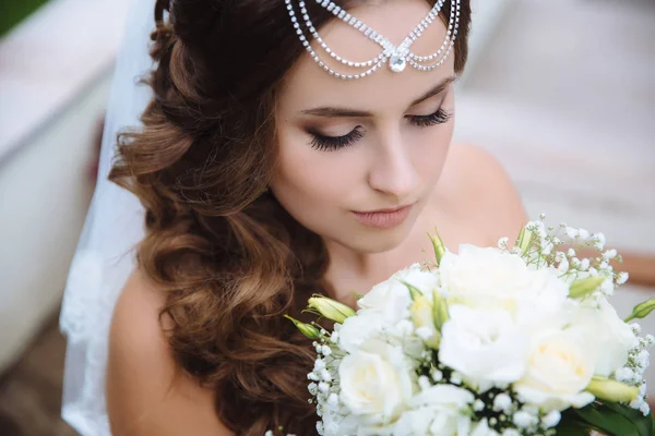 Vista superior de um close-up de uma noiva grega admirando seu buquê branco de rosas, abaixou os olhos para baixo, mostrando suas pestanas longas grossas . — Fotografia de Stock