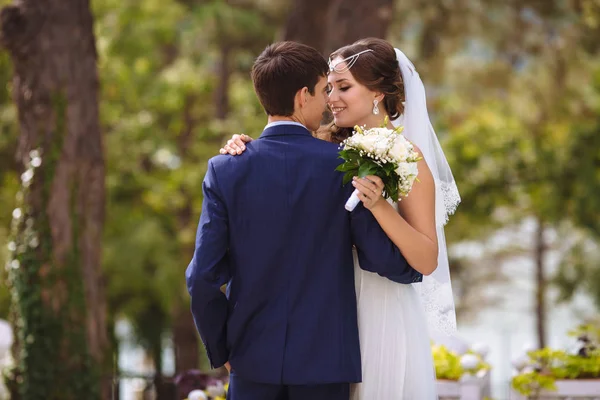 Braut und Bräutigam verbringen ihren Hochzeitstag allein. Sie umarmen und küssen sich sanft und haben Spaß beim Spazierengehen im Park. — Stockfoto
