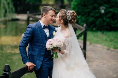 Modern takım elbiseli bir adam ve bir kız bir düğün elbise kucaklama ve birbirleriyle düğün günlerinde bask. Gelin güzel bir buket tutarak ve gülümseyen.