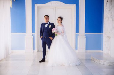 Gelin ve damat evlilik töreni kolundan girmek hazırlanıyor. Gülümse ve şenlikli giysileri düğün günün tadını çıkarın.