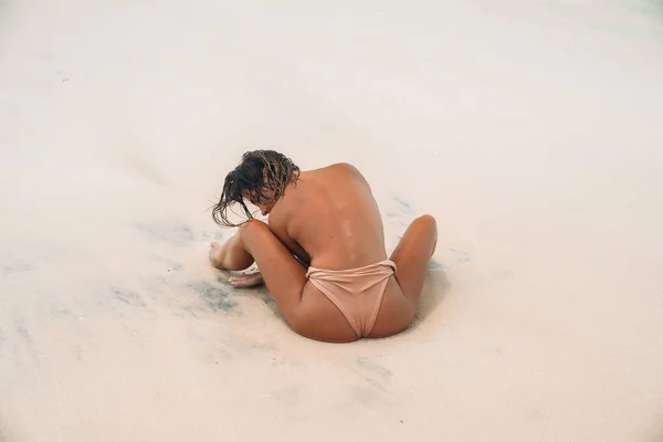 Rückansicht sexy Arsch von sportlichen Mädchen in beigem Badeanzug am Strand des Ozeans. Teil des weiblichen Körpers, nackter Rücken und Schultern. gebräunte Booties des jungen Models im Bikini ohne BH. — Stockfoto