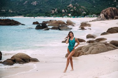 Issız bir tropik tatil keyfini Akuamarin quill içindeki ince, güneşten genç kız sahilde taşlarla, beyaz kumlu bir plaj üzerinde duruyor.