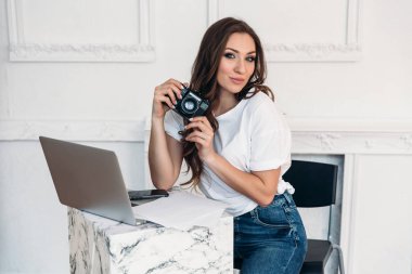 Onu kamera ile poz güzel sevimli kadın fotoğrafçı. Kız geldi bir kafe, bir dizüstü bilgisayar ve bir smartphone için işleme fotoğraf istiyor.