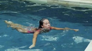 Seksi bir sporcumuz yelken havuzda sıcak yaz günü sahiptir, denizden çıkar, dirsek havuzun kenarında olur. Güzel, kayan bir kız Avrupa görünüm bir yavaş çekim.
